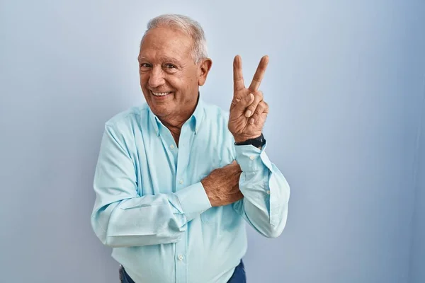 Mavi Arka Planda Gri Saçlı Yaşlı Adam Kameraya Bakıp Gülümsüyor — Stok fotoğraf