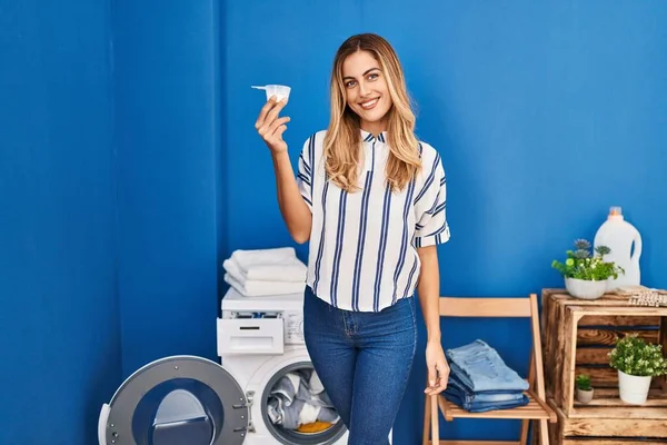 Çamaşır Deterjanı Tutan Genç Sarışın Kadın Pozitif Mutlu Görünüyor Kendine — Stok fotoğraf