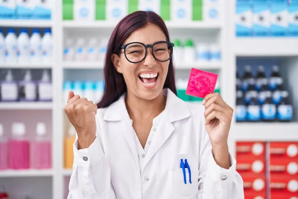 Jovem Hispânica Trabalhando Farmácia Segurando Preservativo Gritando Orgulhoso Celebrando Vitória — Fotografia de Stock