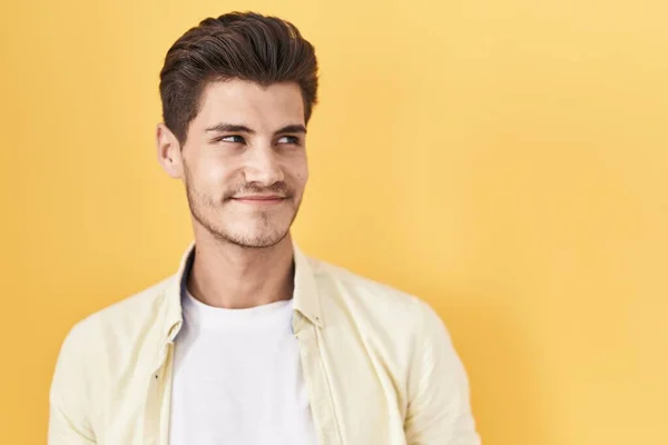 Mladý Hispánec Stojí Nad Žlutým Pozadím Usmívá Dívá Stranou Přemýšlí — Stock fotografie