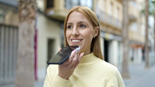 若いですブロンド女性送信音声メッセージとともにスマートフォンでストリート — ストック写真