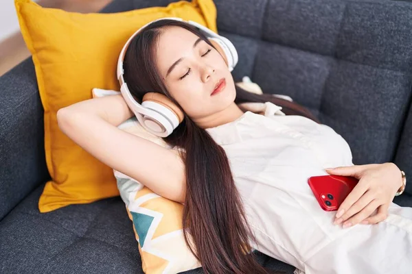 Młoda Chinka Słuchająca Muzyki Śpiąca Kanapie Domu — Zdjęcie stockowe
