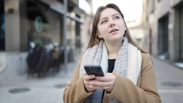 年轻的金发女人在街上用智能手机和轻松的表情 — 图库照片