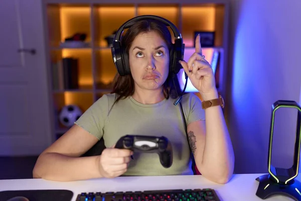 Όμορφη Μελαχρινή Γυναίκα Παίζει Βιντεοπαιχνίδια Φορώντας Ακουστικά Δείχνοντας Επάνω Λυπημένος — Φωτογραφία Αρχείου