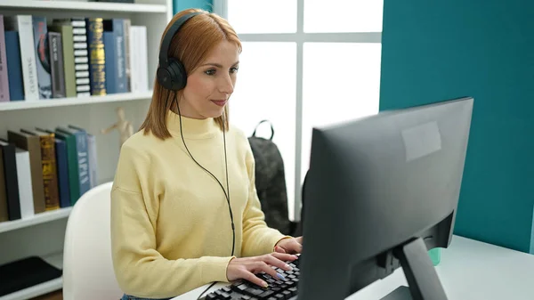 在大学课堂上使用电脑和耳机学习的金发女学生 — 图库照片