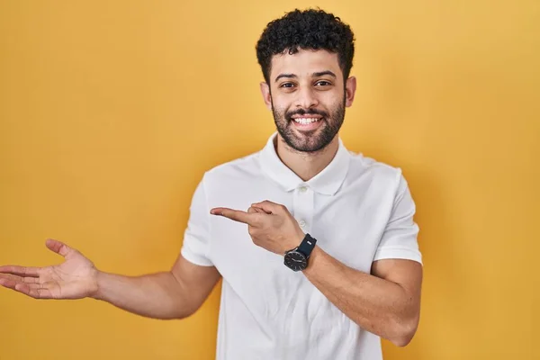 Homem Árabe Sobre Fundo Amarelo Espantado Sorrindo Para Câmera Apresentar — Fotografia de Stock