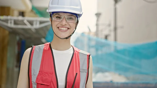 年轻美丽的惊慌失措的女建筑工人站在街上自信地微笑 — 图库照片