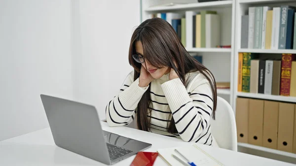 在图书馆大学 年轻美丽的惊慌失措的女学生使用笔记本电脑缓解宫颈疼痛 — 图库照片