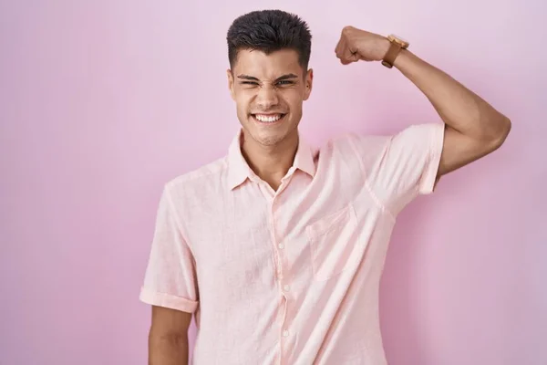 Młody Hiszpan Stojący Nad Różowym Tłem Silna Osoba Pokazująca Mięśnie — Zdjęcie stockowe