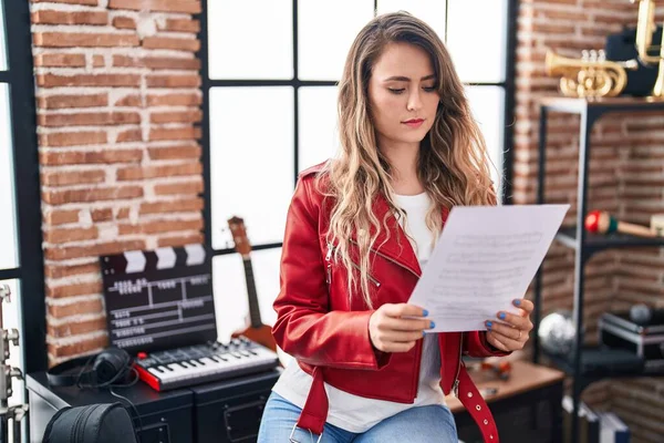 Young woman artist reading music sheet at music studio