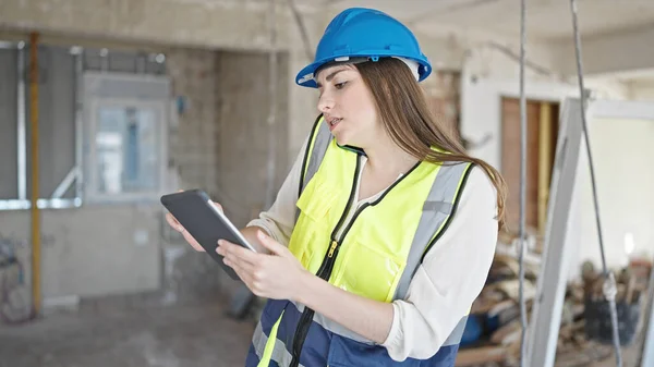 年轻美丽的惊慌失措的女建筑商在建筑工地用触摸板用智能手机交谈 — 图库照片