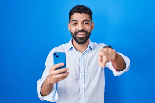 一个留着胡子的西班牙男人用智能手机打字 用手指指着你和相机 面带微笑 面带微笑 — 图库照片