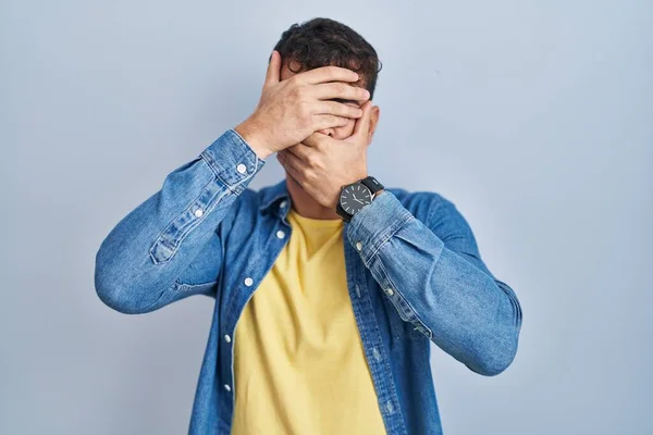 Jovem Hispânico Sobre Fundo Azul Cobrindo Olhos Boca Com Mãos — Fotografia de Stock