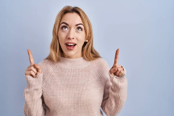 Hispanic Woman Standing Blue Background Amazed Surprised Looking Pointing Fingers — Stockfoto