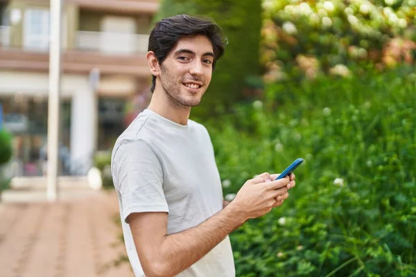 Joven Hombre Hispano Sonriendo Confiado Usando Smartphone Parque —  Fotos de Stock