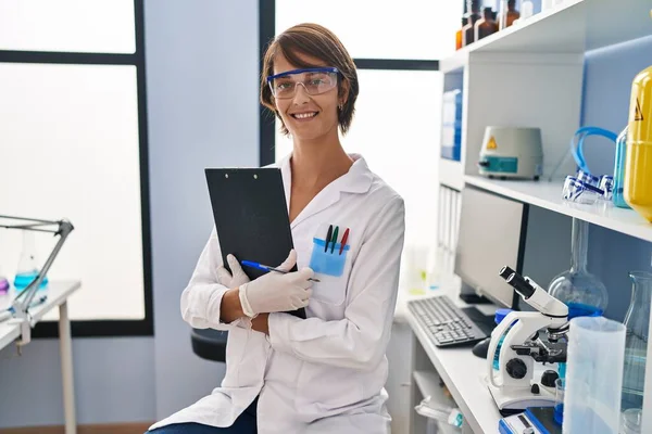 Joven Hermosa Mujer Hispana Científica Sonriendo Confiada Sosteniendo Portapapeles Laboratorio — Foto de Stock