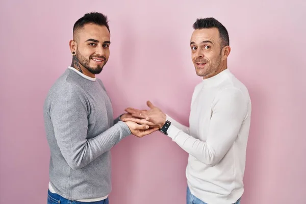 Homoszexuális Pár Áll Rózsaszín Háttér Felé Mutató Kezét Nyitott Tenyérrel — Stock Fotó