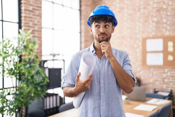 顎に手で質問について真剣に考えて建設事務所で建築家のハードハットを身に着けているひげを持つアラブ人男性 混乱のアイデアについて思慮深く — ストック写真