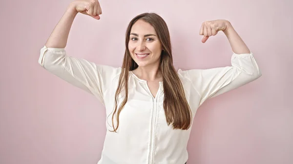 stock image Young beautiful hispanic woman smiling confident doing strong gesture with arms over isolated pink background