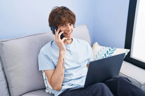 Young Blond Man Talking Smartphone Using Laptop Home — Fotografia de Stock
