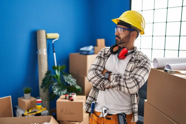 腕を組んで横に見て家の改装で働いて髭を生やしている若いヒスパニック系の男は確信と自信を越え — ストック写真