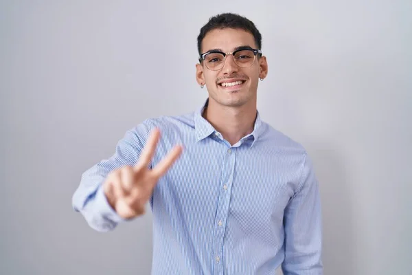 ビジネス用の服を着たハンサムなヒスパニック系の男性とメガネは 指の勝利の兆候を行うことを示すカメラを見て笑っている — ストック写真