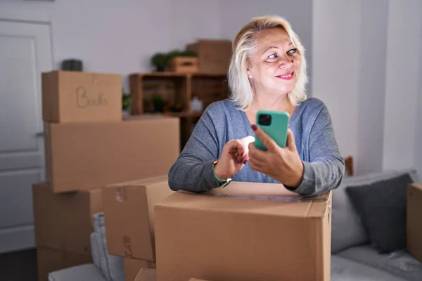 Middle Age Blonde Woman Smiling Confident Using Smartphone New Home — ストック写真