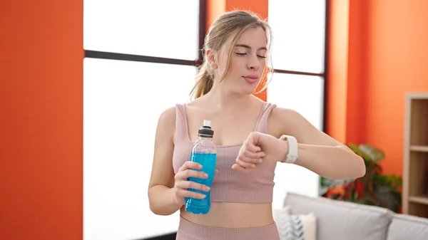 Młoda Blondynka Ubrana Odzież Sportową Trzyma Napój Energetyczny Patrząc Stoper — Zdjęcie stockowe