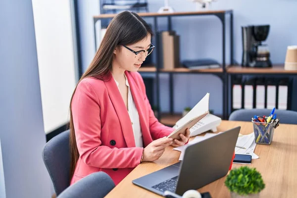オフィスでノートパソコンの読書本を使用して中国の女性ビジネスワーカー — ストック写真