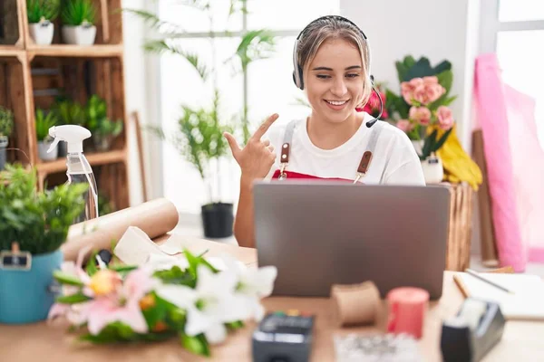 Çiçekçide çalışan genç sarışın kadın video çekiyor. Gülümsüyor, mutlu bir şekilde işaret ediyor. 