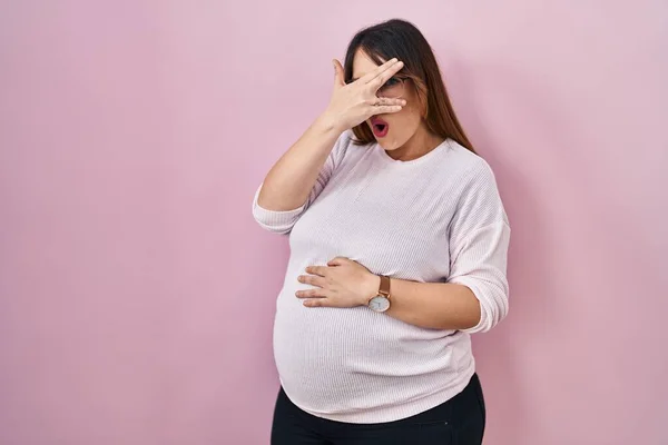 Zwangere Vrouw Staan Roze Achtergrond Gluren Shock Bedekken Gezicht Ogen — Stockfoto