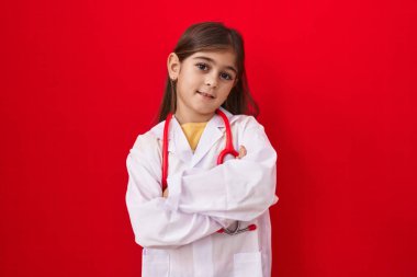Doktor üniforması giyen, steteskopla gülümseyen, kollarını kavuşturup kameraya bakan İspanyol bir kız. pozitif kişi. 