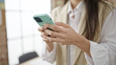 Ofiste akıllı telefon kullanan güzel bir İspanyol kadın.