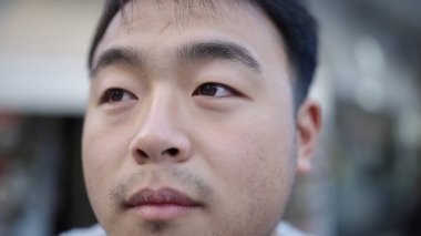 Young chinese man looking to the side with serious expression at street