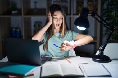 Genç kız gece geç saatte evde ödev yapıyor. Saate bakıyor, endişeleniyor, geç kalmaktan korkuyor. 