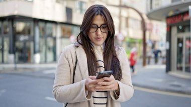 Genç ve güzel İspanyol kadın akıllı telefon kullanıyor. Sokakta ciddi bir ifadesi var.