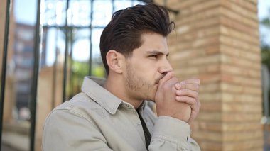 Sokağın ortasında soğuk hava üfleyen genç İspanyol adam.