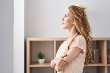 Kolları çapraz hareket eden genç sarışın kadın ve evde ciddi bir ifade.