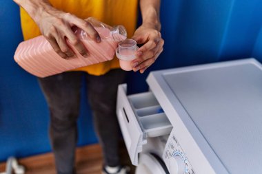 Young blond man pouring detergent at laundry room