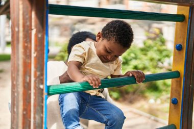 Baba ve oğul oyun alanında kaydırak oynuyorlar.