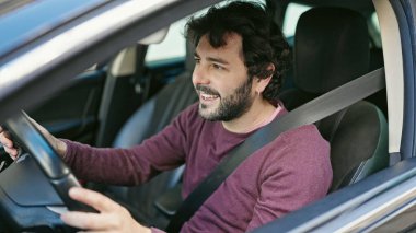 Young hispanic man smiling confident driving car at street