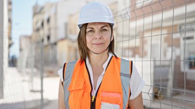 Orta yaşlı İspanyol kadın inşaatçı inşaat alanında duruyor.