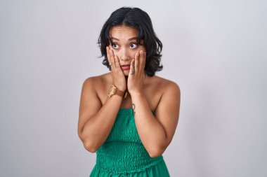 Genç İspanyol kadın izole arka planda duruyor. Yorgun eller yüzünü, depresyonunu ve üzüntüsünü kapatıyor. Sorunlar yüzünden üzgün ve sinirli. 