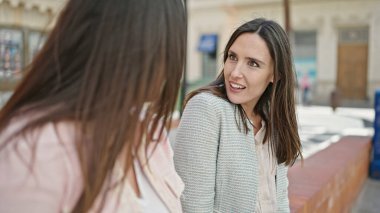 İki kadın sokakta kendinden emin bir şekilde gülümsüyor.