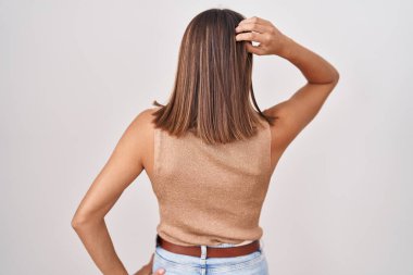 Young hispanic woman standing over white background backwards thinking about doubt with hand on head 