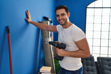 Genç İspanyol adam gülümsüyor. Yeni evinde kendine güveni tam.