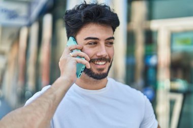 Genç İspanyol adam gülümsüyor. Kendine güveniyor. Sokakta akıllı telefondan konuşuyor.