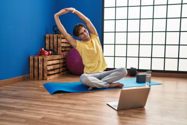 Young caucasian man smiling confident having online stretching class at sport center