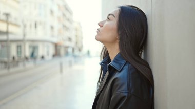 Genç ve güzel İspanyol kadın sokağın karşısında üzgün bir ifadeyle yan tarafa bakıyor.