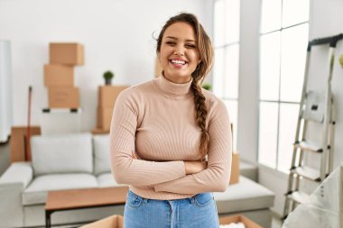 Young beautiful hispanic woman smiling confident standing with arms crossed gesture at new home